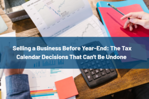 Blue title banner over a workspace with charts, a calculator, and notebooks about selling a business before year-end tax decisions.
